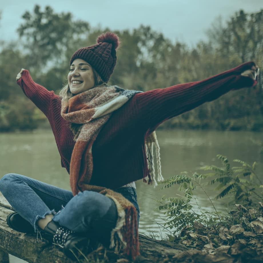 Woman in fall weather clothing stretching her arms and smiling.